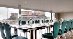 Penthouse Boardroom  With Green Seating Around Table With Water Bottles, Window With Open Drapes and City View