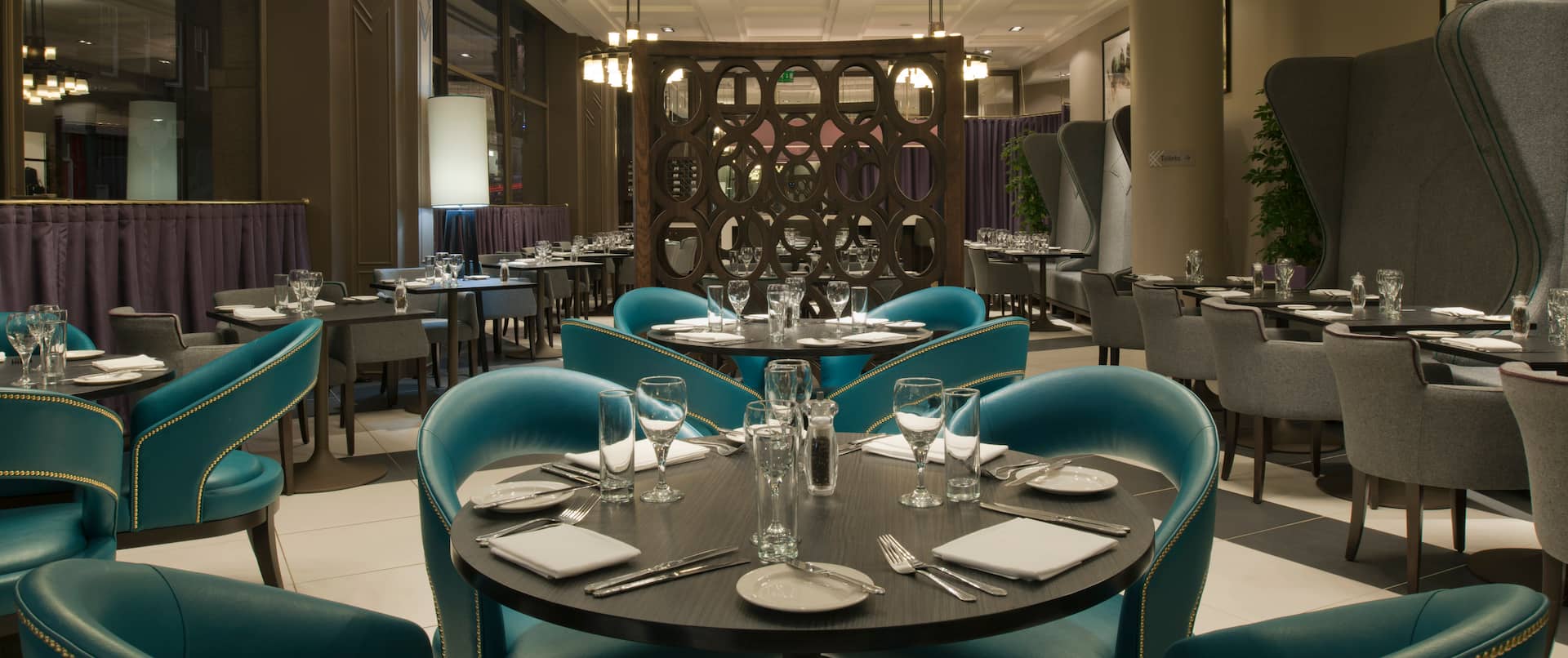 Booths, Green Chairs, Dining Tables With Place Settings and Glasses in Bread Street Brasserie Restaurant