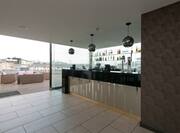 Decorative Lighting Above Service Area of Fully Stocked Bar, Soft Seating and Tables on Terrace With City View