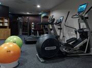 Fitness Center With Yellow and Green Exercise Balls, Towel Station, Weight Machine, Weight Balls, Free Weights, and Cardio Equipment