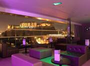 Purple Lighting, Lounge Seating, and Large Window With View of Illuminated City at Night in SkyBar