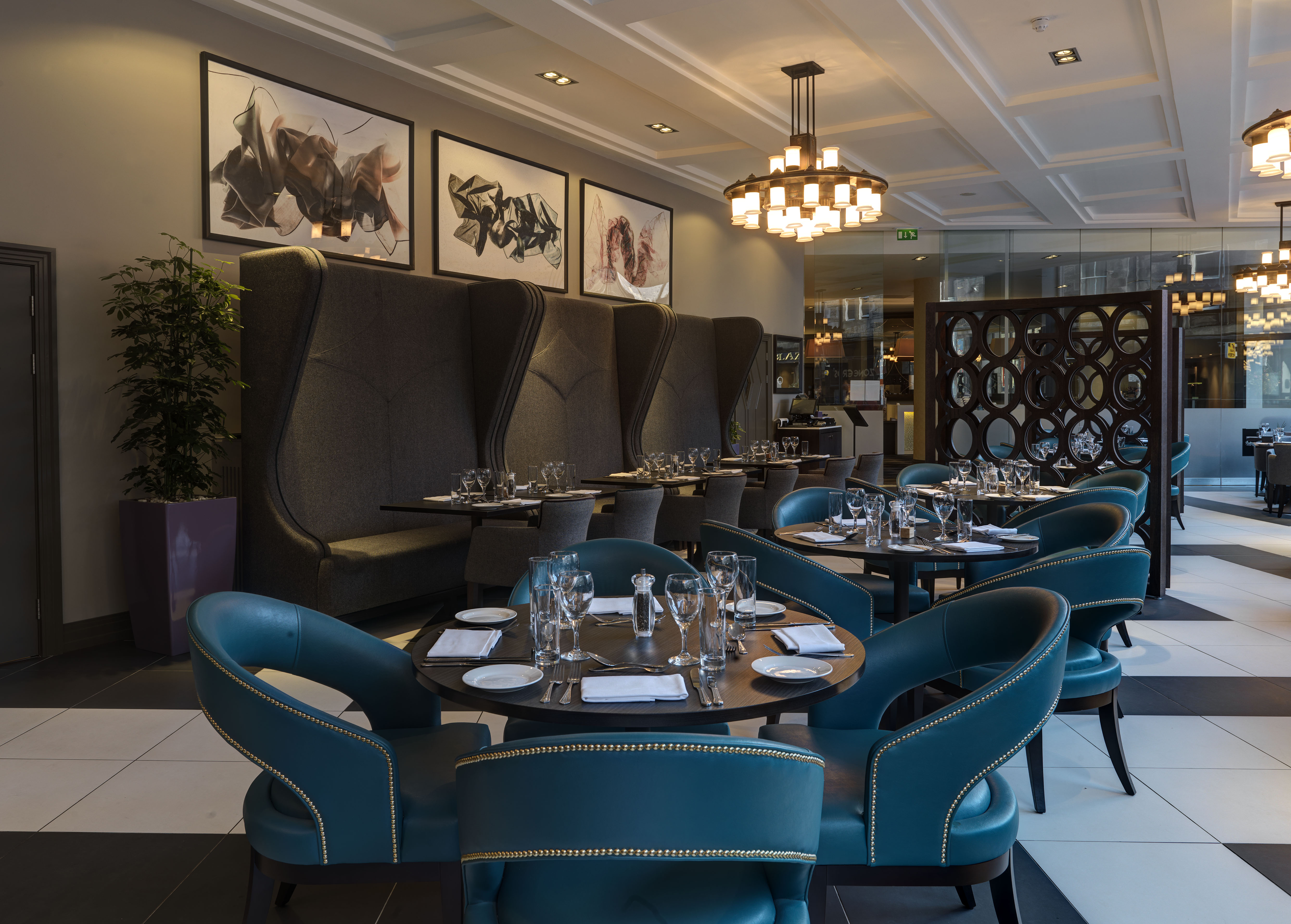 Wall Art, Booths, Green Chairs and Dining Tables With Place Settings and Glasses in Bread Street Brasserie Restaurant