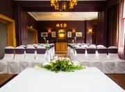 Flowers on Table With White Linens and White Chairs With Purple Sashes Arranged Theater Style in Wallace Lounge Set Up for Wedding Ceremony
