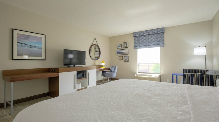 King-Size Bed, Work Desk with Desk Lamp and Chair, Microwave, TV, and Couch in Accessible Guest Room