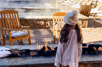 Girl in cozy hat looking out at snowy seating area and pergola