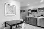 Spacious Kitchen Area In Suite Featuring Dining Table, Refrigerator, Dishwasher, And Microwave