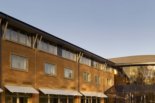 Daytime View of Hotel Exterior, Signage, Moat With Fountains, Landscaping, Entrance and  Parking Lot