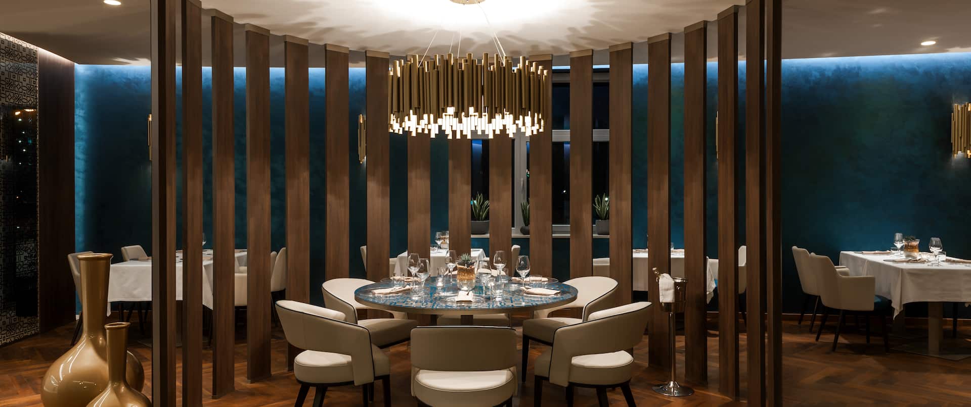 Circular Dining Area With Wood Partition, Seating For Six at Round Table Under Chandelier in Restaurant Gold