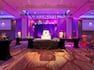 Dramatically Lit Ballroom Set Up for Wedding Reception With Two Large Projector Screens, Performance Stage and Black Cocktail Tables