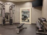 Fitness Center With Weight Machine, Bench, Large Mirror With Reflection of Cardio Equipment, TV, and Free Weights