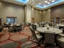 Round Dining Tables With Napkins and Flowers, Chairs, Podium and Entry Doors in Ballroom