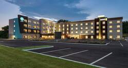 Modern dual property hotel exterior featuring glowing guestrooms, large parking lot, and beautiful dusk sky