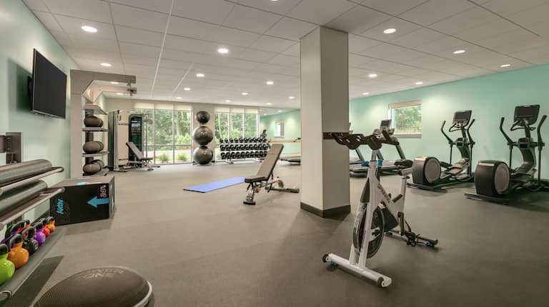 Bright fitness center fully equipped with new cardio machines weights and TV 