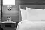 Comfortable guestroom bed, headboard, wall sconce, and side table.