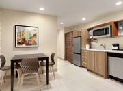 Bright kitchen area in suite featuring dining table, dishwasher, microwave, and refridgerator.