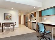 Bright living area in accessible suite featuring work desk, dining area, and fully equipped kitchen.
