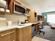 Bright studio suite featuring fully equipped kitchen, work desk, TV, and comfortable king bed.