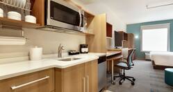 Bright studio suite featuring fully equipped kitchen, work desk, TV, and comfortable king bed.