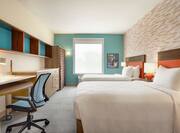 Bright studio suite featuring work desk, two comfortable queen beds, and ample storage.