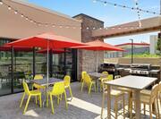 Beautiful outdoor patio featuring patio tables, string lights, and complimentary barbaque grills for guests to enjoy.