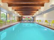 Spacious indoor swimming pool featuring large windows, ample seating, and stunning wood beams on the ceiling.