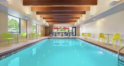 Spacious indoor swimming pool featuring large windows, ample seating, and stunning wood beams on the ceiling.