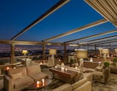 Rooftop Terrace Seating With Candlelit Tables, Illuminated Lamps and Open Ceiling at Night