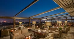 Rooftop Terrace Seating With Candlelit Tables, Illuminated Lamps and Open Ceiling at Night