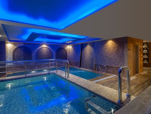 Blue-Lit Indoor Pool With View of Towel Room