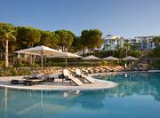 The tree-lined pool at Conrad Algarve with sun loungers.