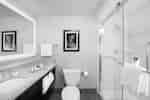 Large Vanity Mirror, Sink, Fresh Towels, Amenities, Toiletries, Wall Art Above Toilet, and Shower With Glass Doors