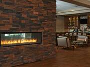 Brick Fireplace in Lobby Lounge Area With oft Seating and View of Bartender at Full Stocked Bar