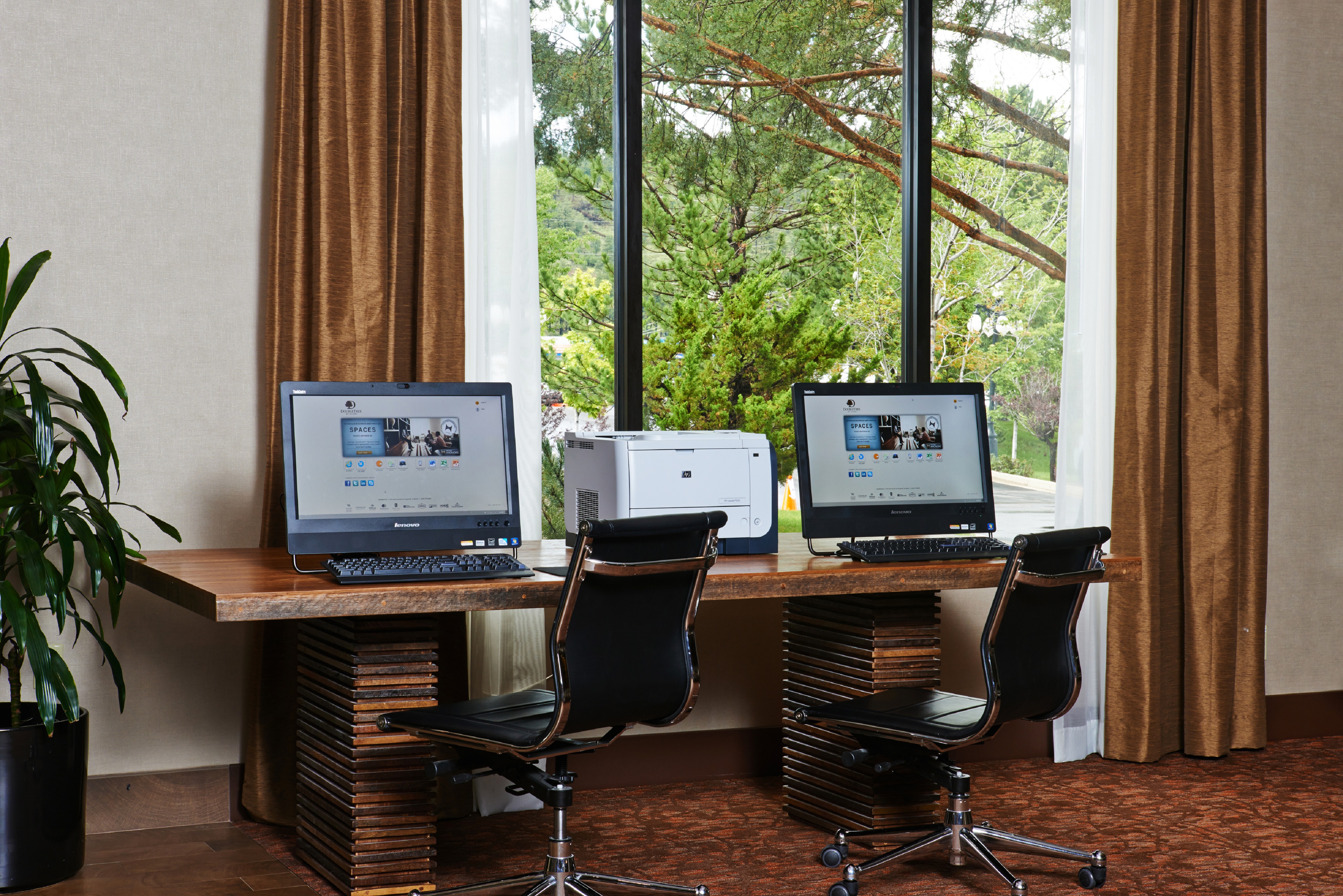 Business Center With Two Computers and Printer on Work Desk by Window With Open Drapes