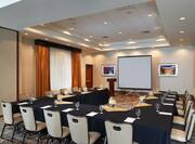 Meeting Room With Water Pitchers, Napkins, and Drinkware on U-Shaped Table With Black Linens, Chairs, Windows With Closed Drapes, Entry Doors, Wall Art, Podium and Presentation Screen