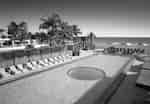 Área de la piscina de borde infinito con divanes y vista a la playa