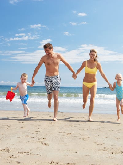Family of Four Running Hand-in-Hand on Beach