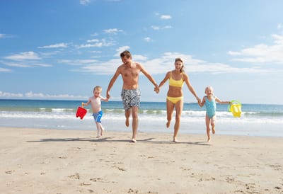 Family of Four Running Hand-in-Hand on Beach