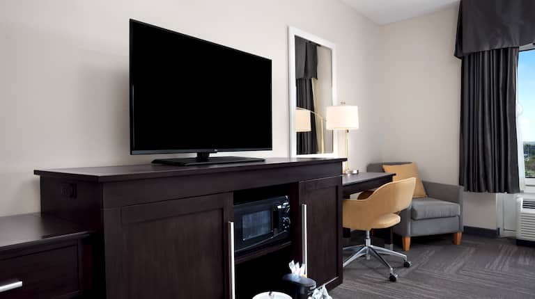 Televisor de alta definición, horno de microondas, cafetera, escritorio y sillón en la habitación del hotel 