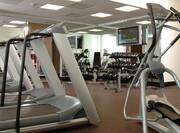 Fitness Center With Cardio Equipment, Mirrored Wall, Weight Benches, TV, and Free Weights