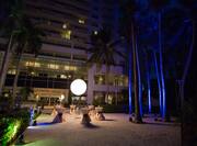Illuminated Palm Trees, Hotel Exterior and Patio With Cocktail Tables Set Up for Evening Reception
