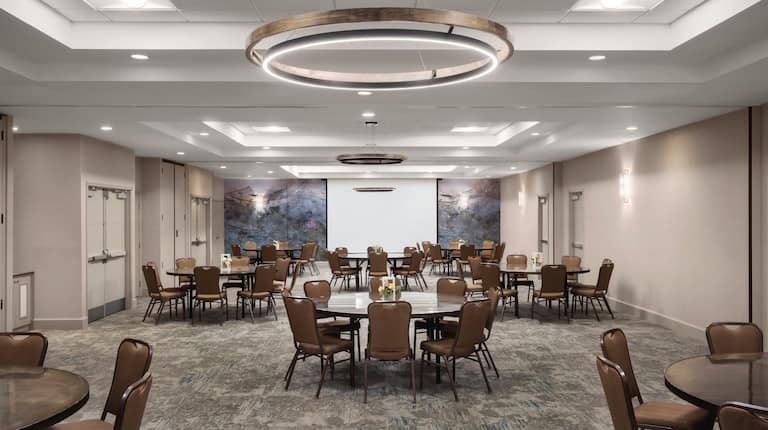 Spacious on-site meeting room featuring banquet setup and projector screen at front of room.