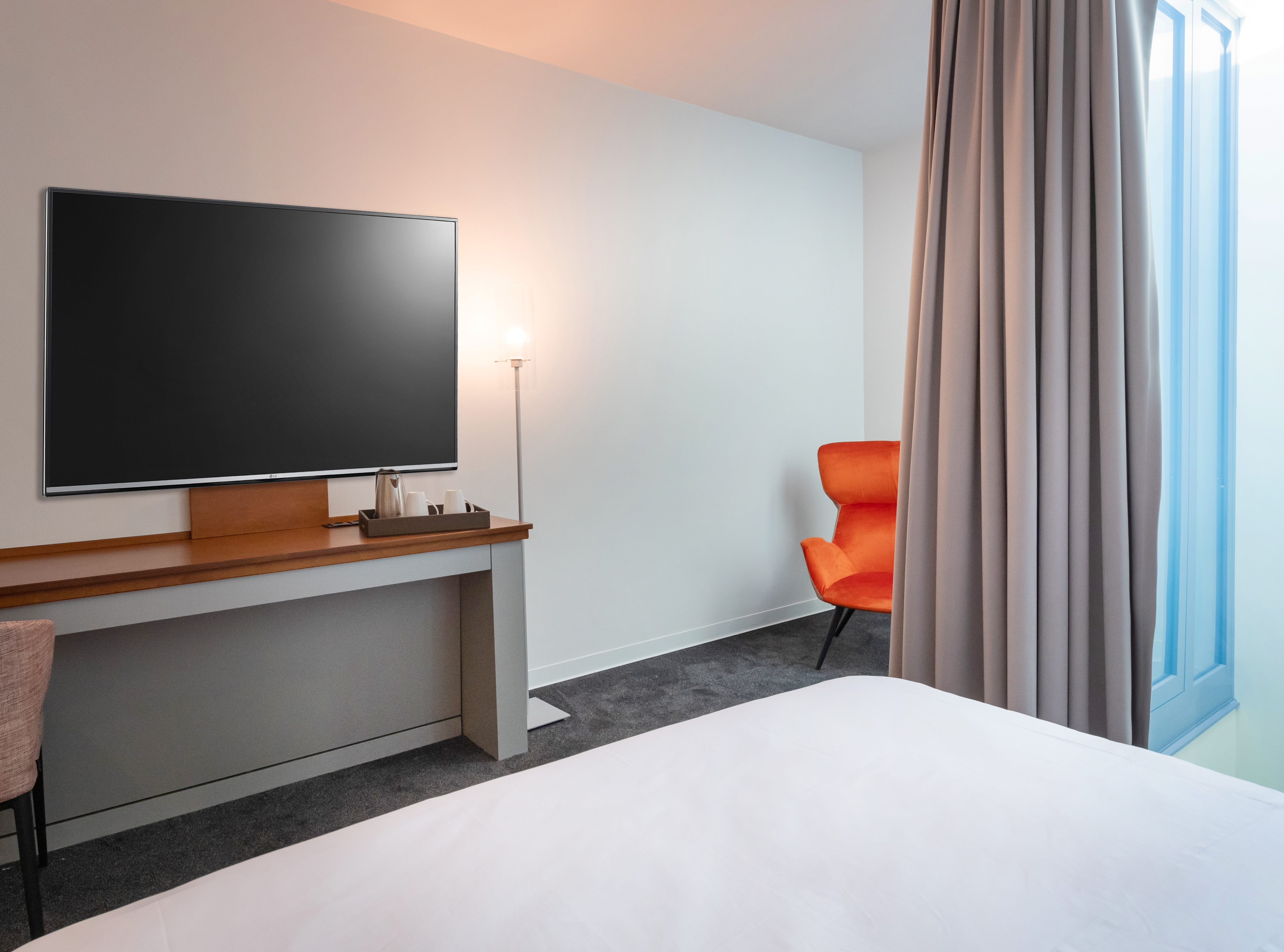 HD-Fernseher, Bett und Sessel in der Hotelsuite