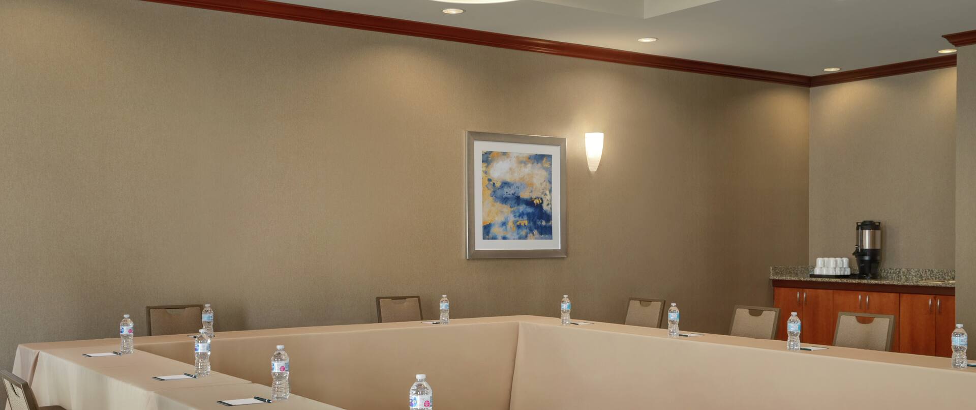 Spacious meeting room fully equipped with u shape table, notepads with pens, and refreshments.