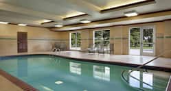 Bright indoor swimming pool area featuring large windows with beautiful outdoor view. 