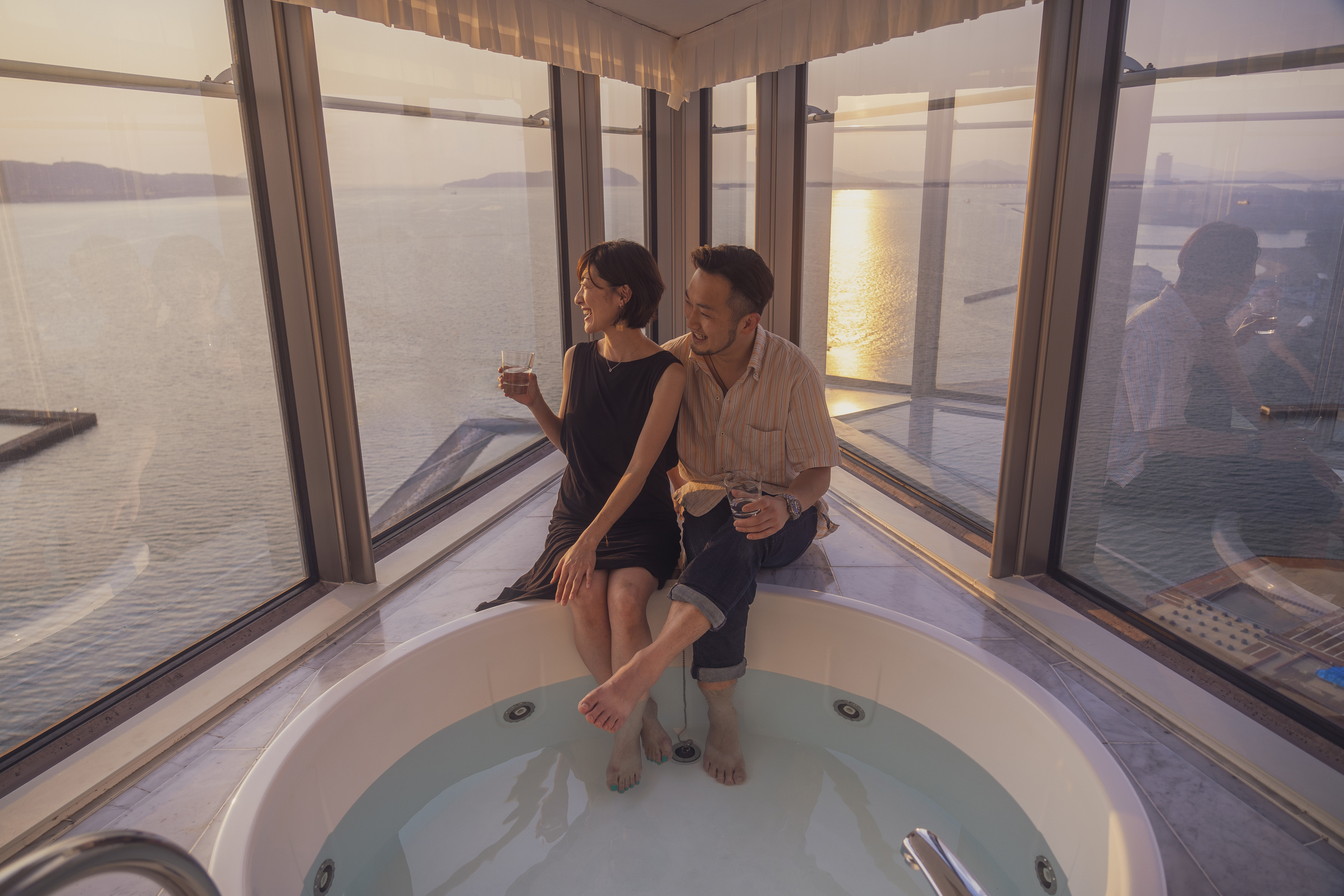 Couple in a Jetted Tub Enjoying the View from a Guest Room with Large Windows