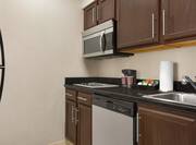 Functional in suite kitchen featuring fridge, dishwasher, microwave, coffee maker, and cooktop stove.