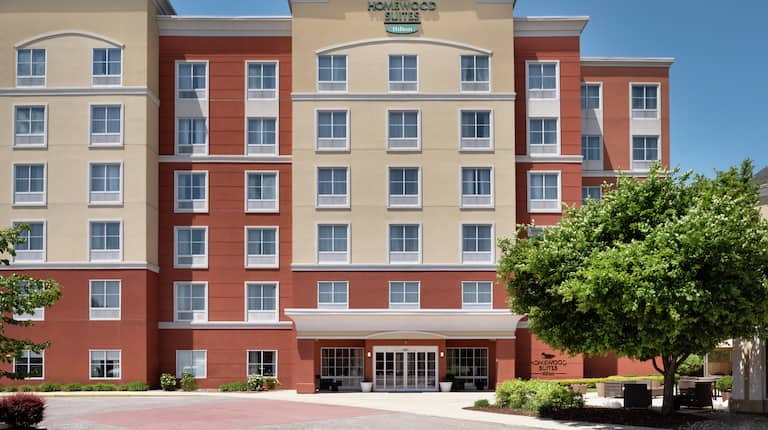  Welcoming Homewood Suites hotel featuring bright blue skies and lush trees.