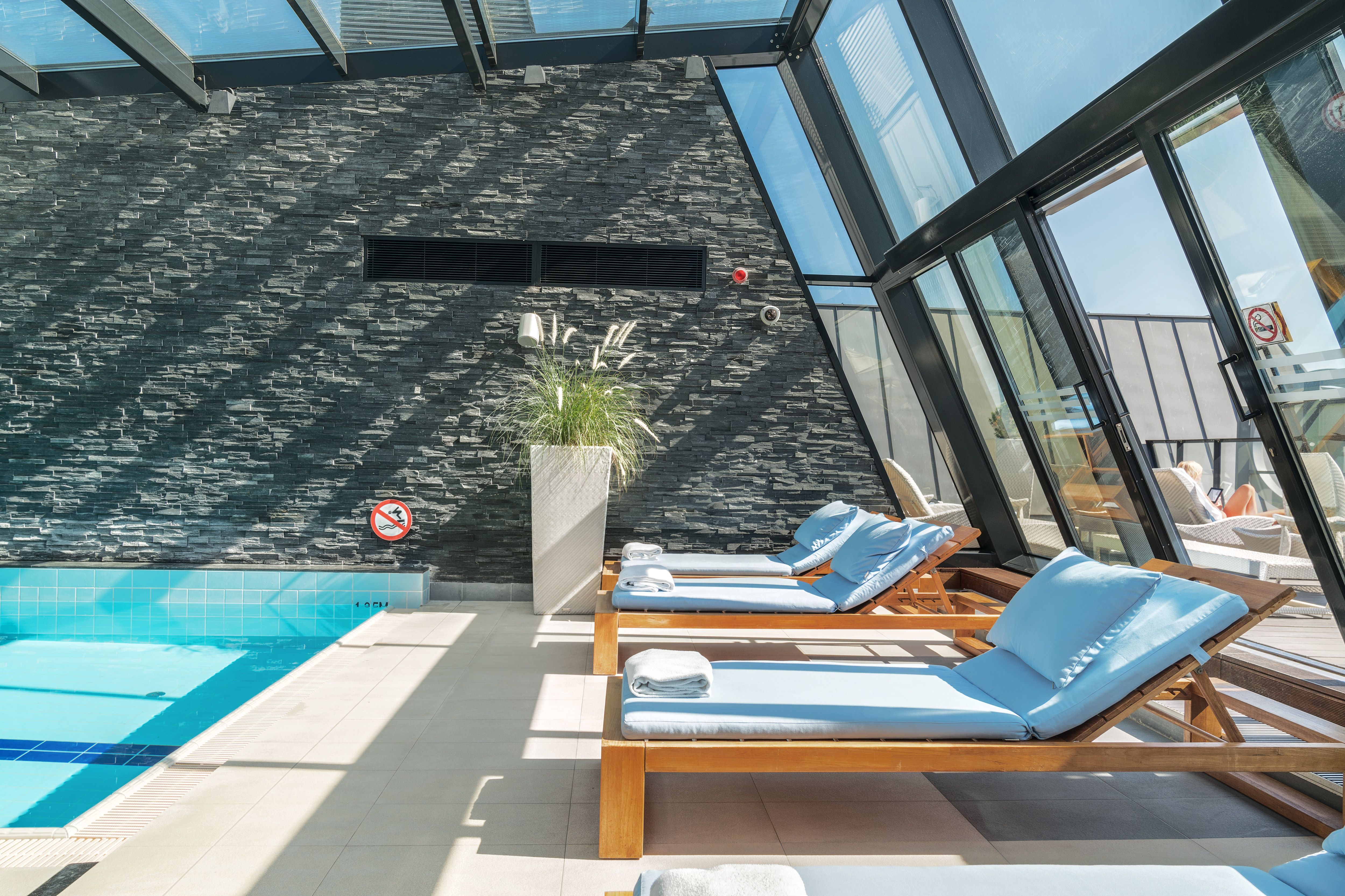 Indoor Pool Area with Large Windows and Lounge Chairs