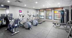 Fitness center area with treadmills, ellipticals, and weight benches