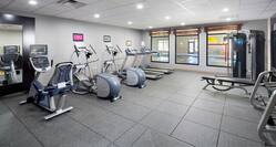 Fitness center area with treadmills, ellipticals, and weight benches